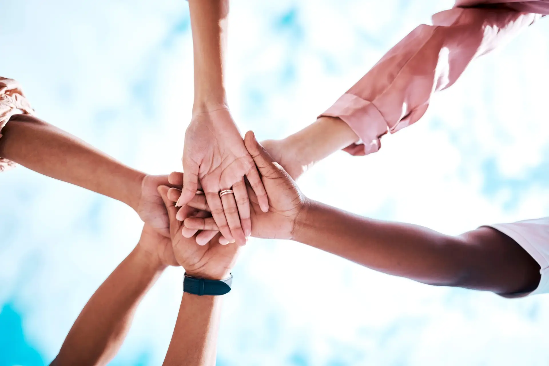 hands stacked motivation and team building on a blue sky for trust community and about us missio